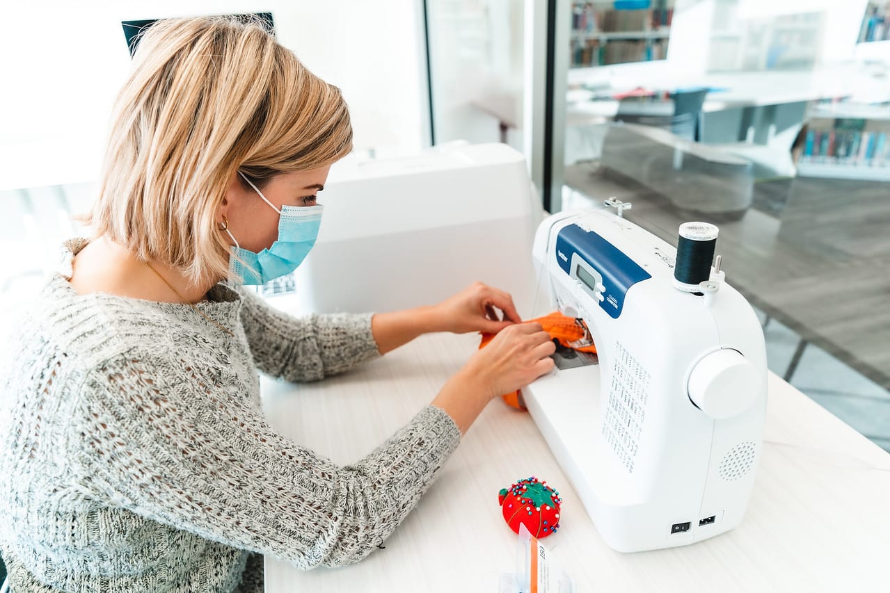 JLV03452-X2 A person wearing a mask and using the sewing machine