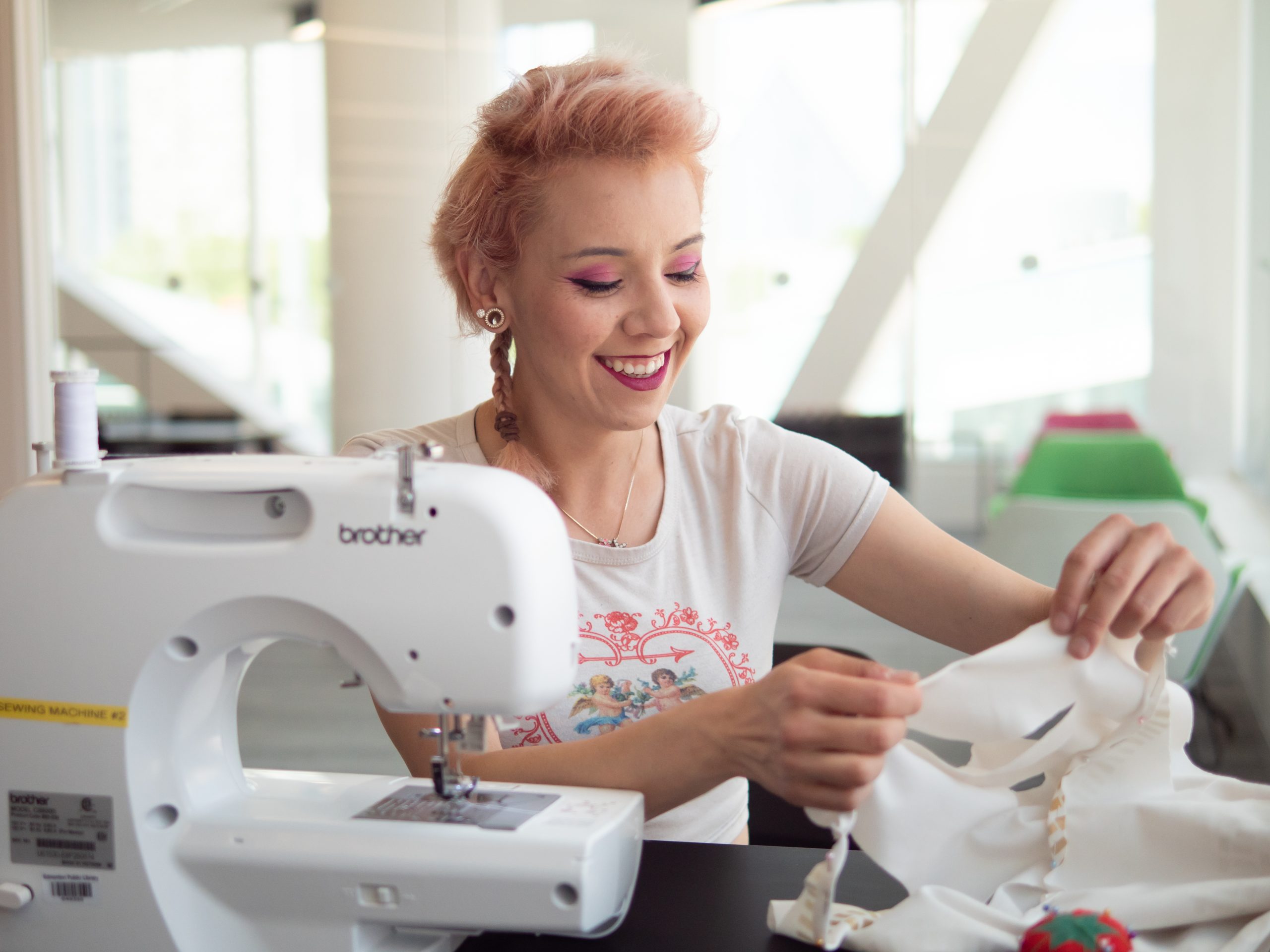 A person smiling while using the sewing machine